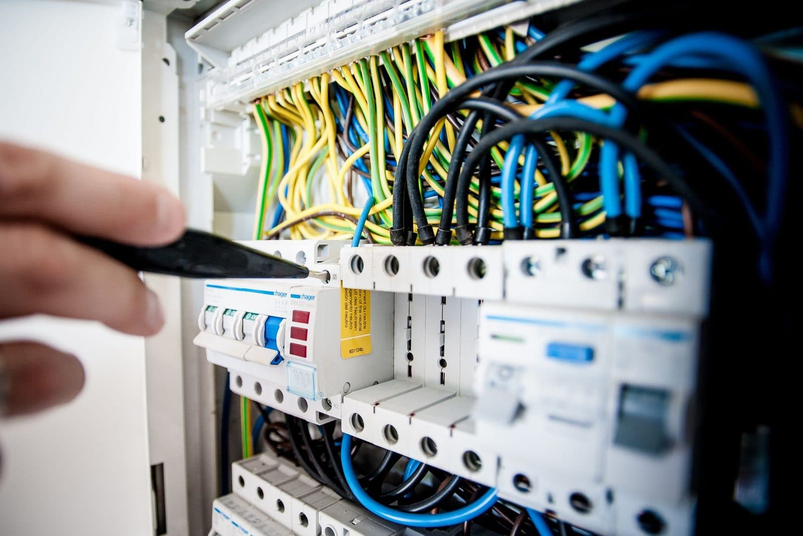 Elektrofachkraft bei der Feinarbeit an einem Sicherungskasten mit Leitungsschutzschaltern